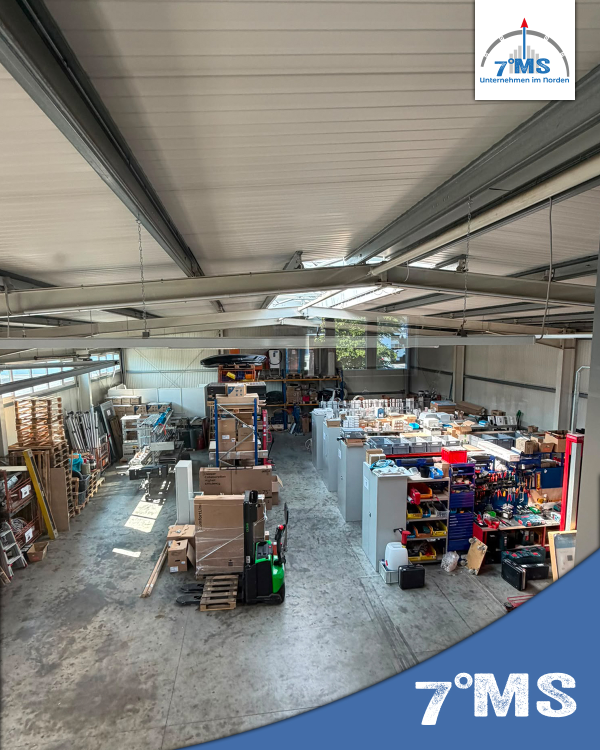 Das Bild zeigt eine Lagerhalle mit verschiedenen Regalen, Kästen und Werkzeugen. Auf der linken Seite sind Holzpaletten und Materialien zu sehen, während auf der rechten Seite das Werkzeug und die Ausrüstung ordentlich angeordnet sind. Eine Gabelstaplerin steht ebenfalls im Raum.